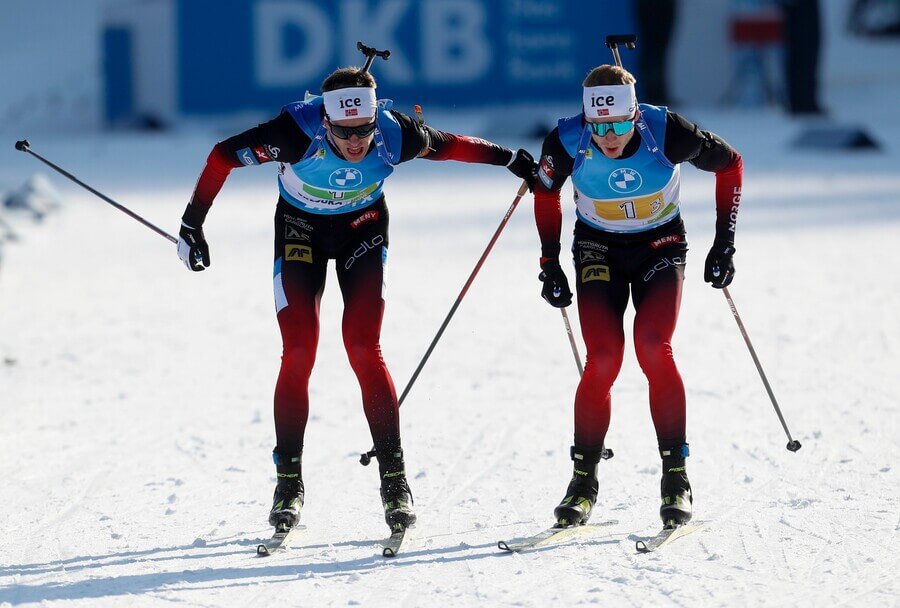 Tarjei Boe (vľavo) a Johannes Thingnes Boe pri odovzdávaní štafety - Zdroj AP Photo/Darko Bandic, Profimedia