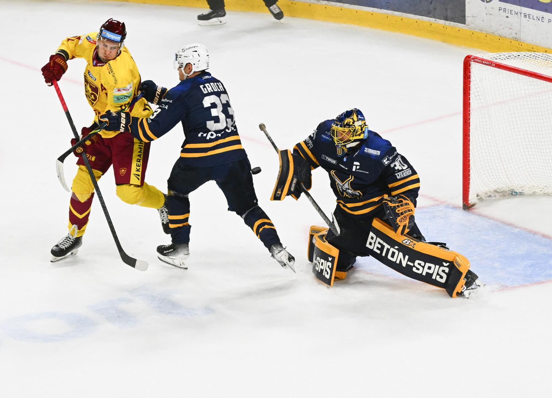 Zľava trenčiansky útočník Filip Ahl pred obrancom Šimonom Grochom a brankárom Denisom Godlom (obaja SNV) v zápase HK Dukla Trenčín vs. HK Spišská Nová Ves v rámci 1. kola Tipsport ligy 2025/2026