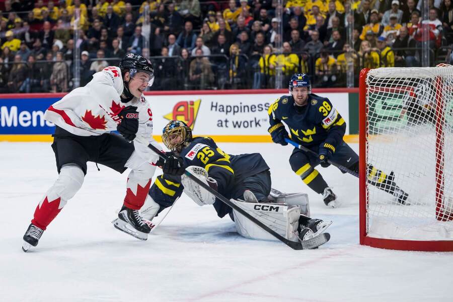 Kanadský útočník Macklin Celebrini (vľavo) prekonáva švédskeho brankára v&nbsp;zápase základnej skupiny A Švédsko vs. Kanada na&nbsp;MS v&nbsp;ľadovom hokeji 2025