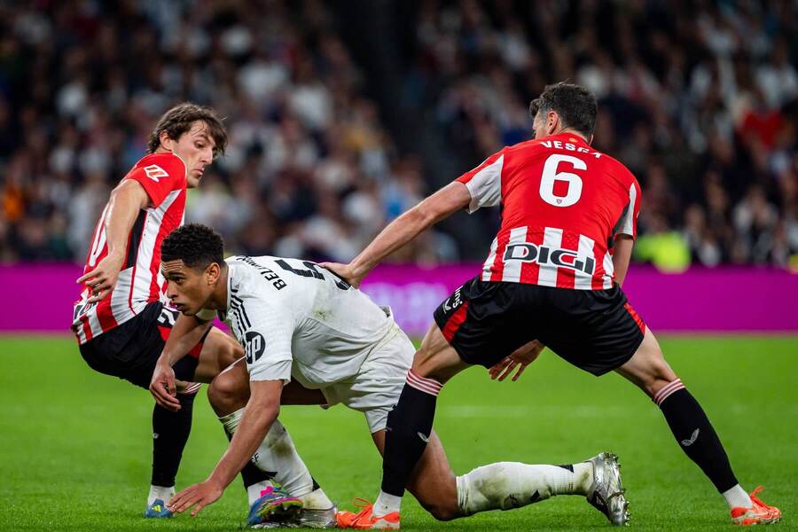 Záložník Realu Jude Bellingham medzi záložníkmi Unaiom Gómezom (vľavo) a&nbsp;Mikelom Vesgom z&nbsp;Bilbaa počas zápasu Real Madrid CF vs. Athletic Bilbao v&nbsp;32. kole La Ligy 2024/2025